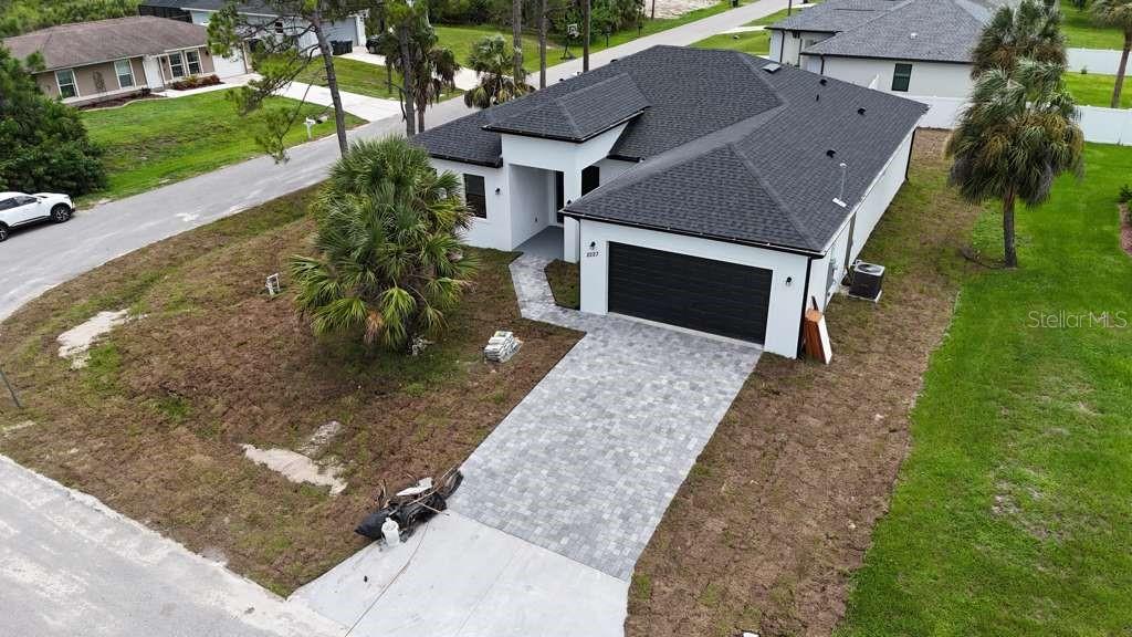 An aerial view shows a modern white house with a dark roof and paved driveway — 2227 SAYBROOK AVENUE, NORTH PORT, FL