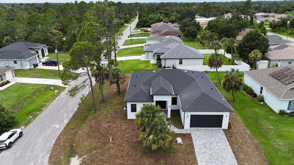 An aerial view shows a modern single-family home with a dark roof and paved driveway — 2227 SAYBROOK AVENUE, NORTH PORT, FL