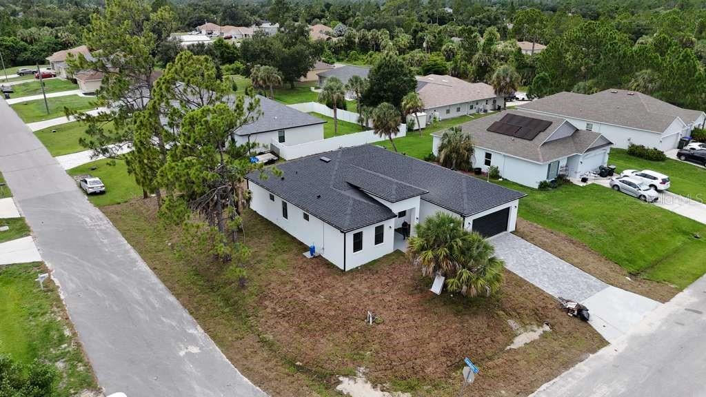 An aerial view shows a white house with a dark roof and a paved driveway — 2227 SAYBROOK AVENUE, NORTH PORT, FL