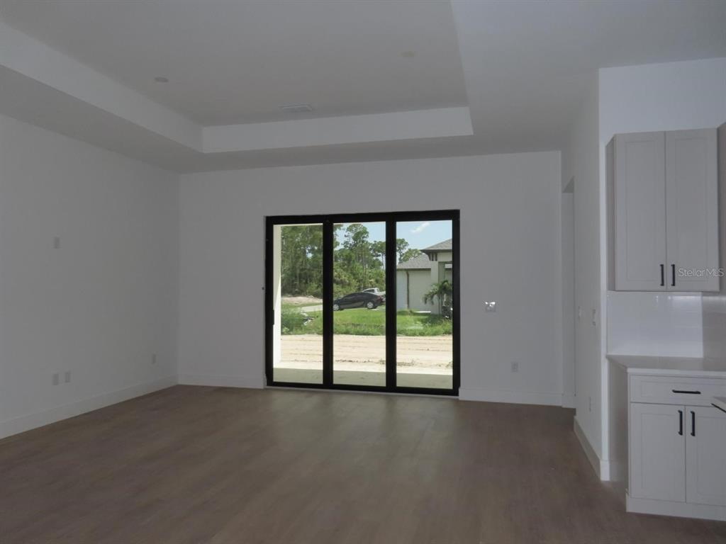 An interior view of a room with light wood floors, white walls, and sliding glass doors — 2227 SAYBROOK AVENUE, NORTH PORT, FL