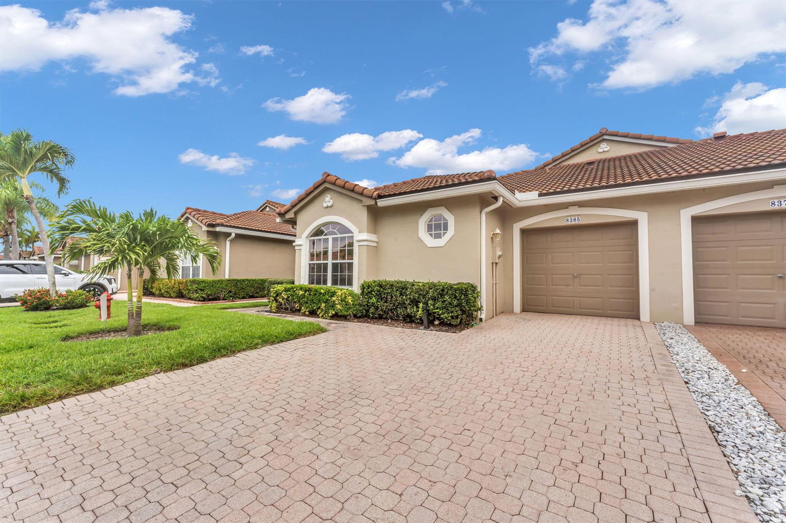 A beige single-story house with a tiled roof, a paved driveway, and a garage — 8385 Vía Serena, Boca Raton FL 33433, BOCA RATON, FL
