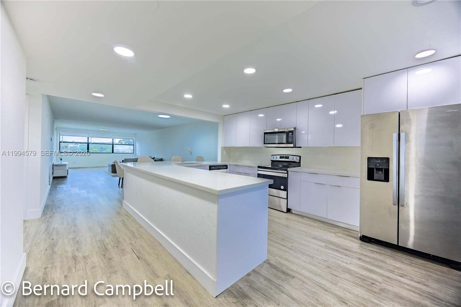 A modern kitchen features white cabinets, stainless steel appliances, and a central island — 2606 NW 104th Ave # 303, Sunrise FL 33322, SUNRISE, FL