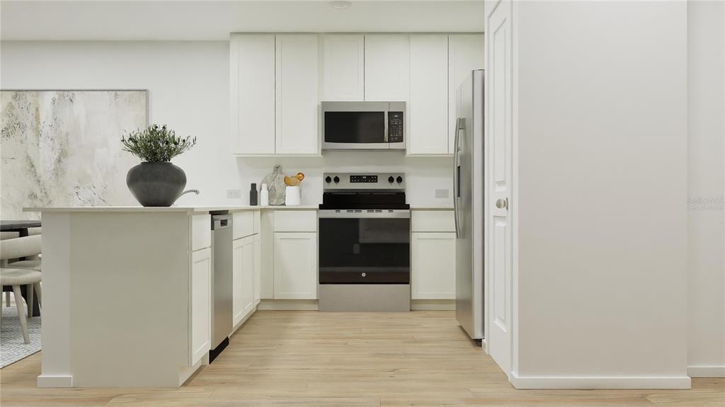 This kitchen features white cabinets, stainless steel appliances, and a small island with seating — 5609 MORANT BAY PATH, KISSIMMEE, FL