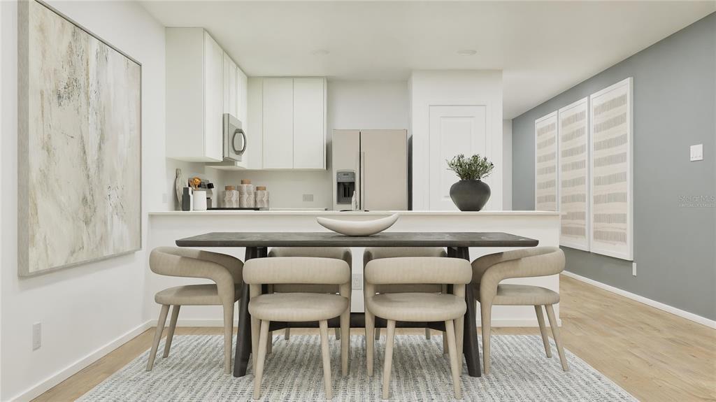 A dining area with a dark table and four chairs sits before a modern kitchen — 5609 MORANT BAY PATH, KISSIMMEE, FL