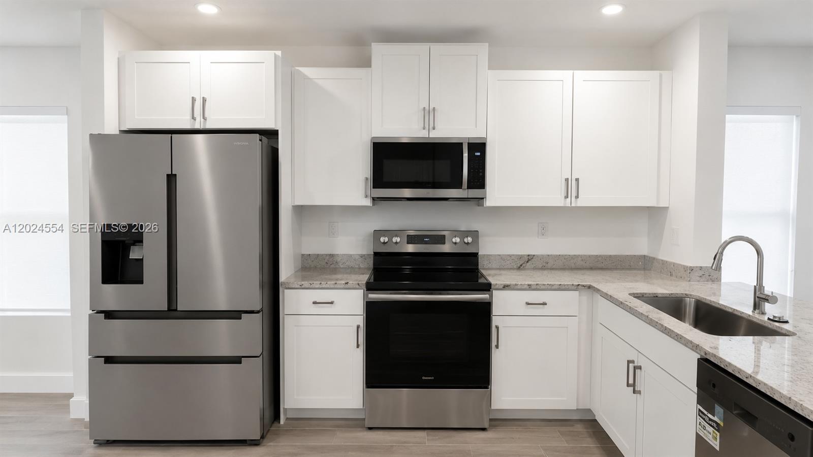 A kitchen features white cabinets, stainless steel appliances, and light-colored granite countertops — 619 NE 4th St, Florida City FL 33034, FLORIDA CITY, FL