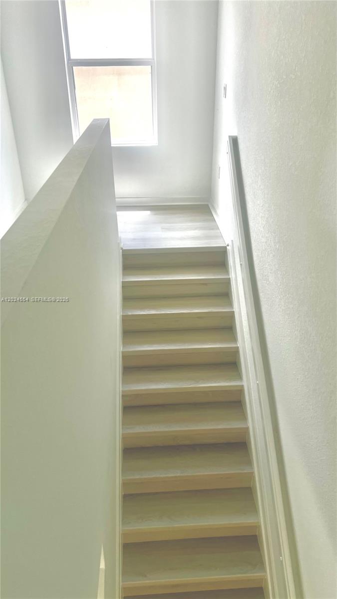 A straight staircase with light wood treads leads to a landing with a large window — 619 NE 4th St, Florida City FL 33034, FLORIDA CITY, FL