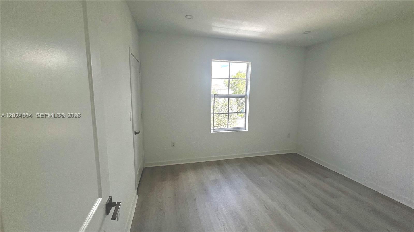 An empty bedroom features light-colored wood-look flooring, white walls, and a single window — 619 NE 4th St, Florida City FL 33034, FLORIDA CITY, FL