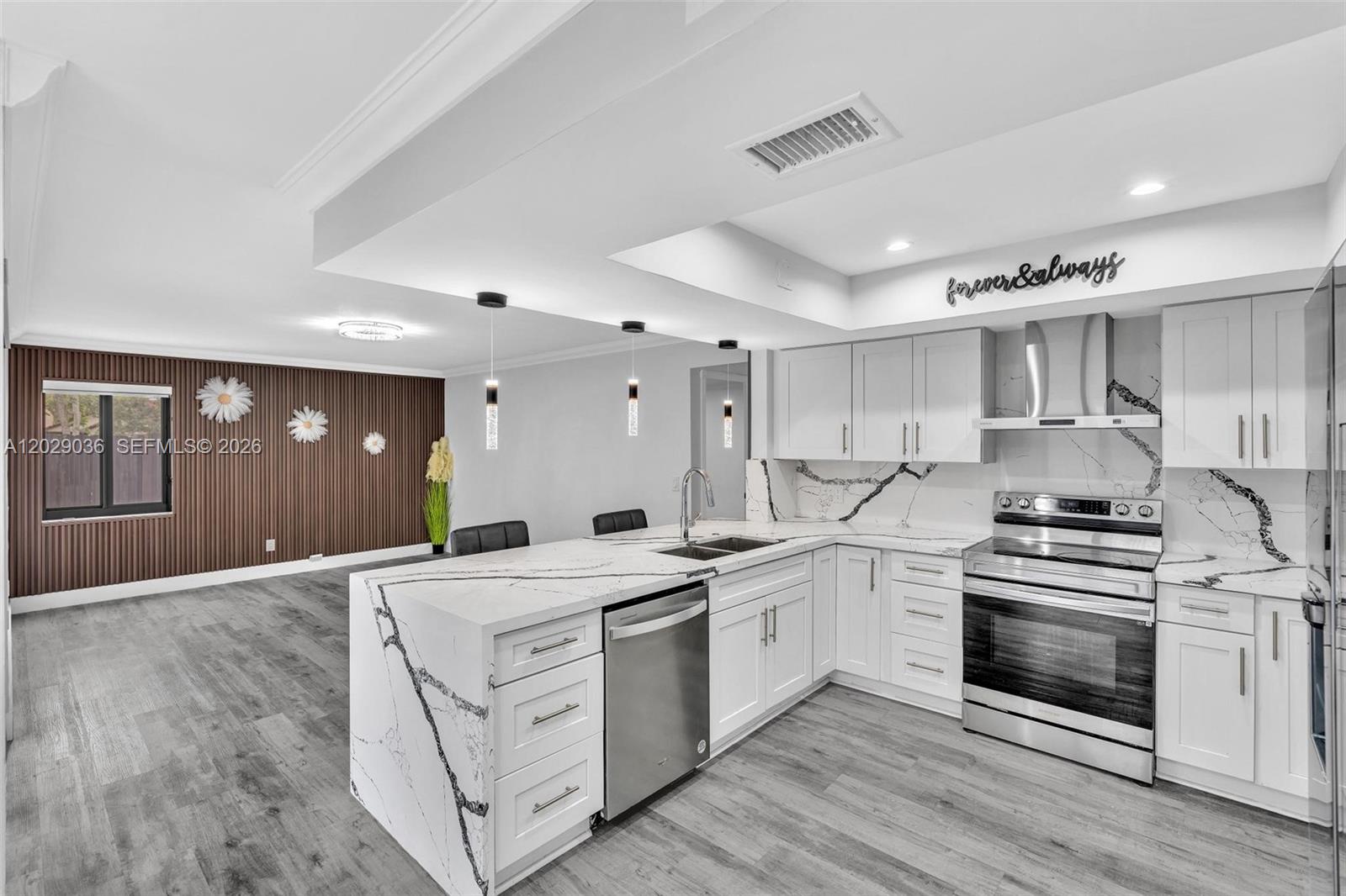 A modern kitchen features white cabinets, marble-patterned countertops, and a wood-slatted accent wall — 17532 NW 61st CT N, Hialeah FL 33015, HIALEAH, FL