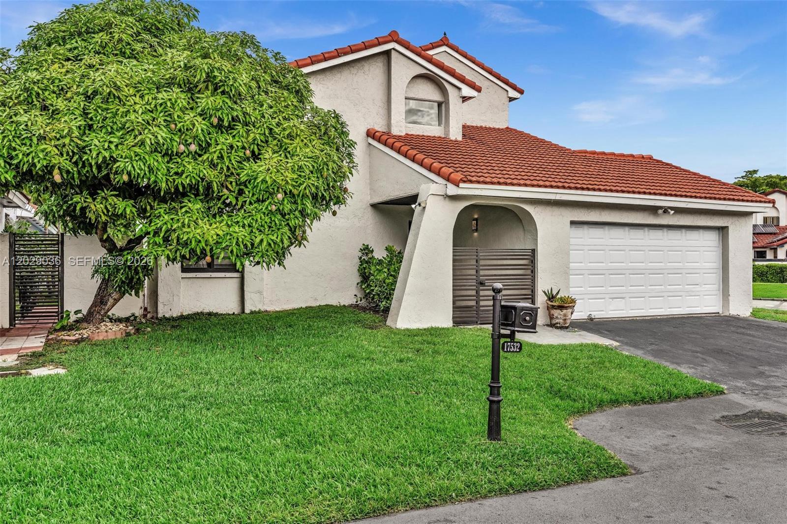 A two-story house with a red tile roof, white stucco exterior, and a large mango tree — 17532 NW 61st CT N, Hialeah FL 33015, HIALEAH, FL