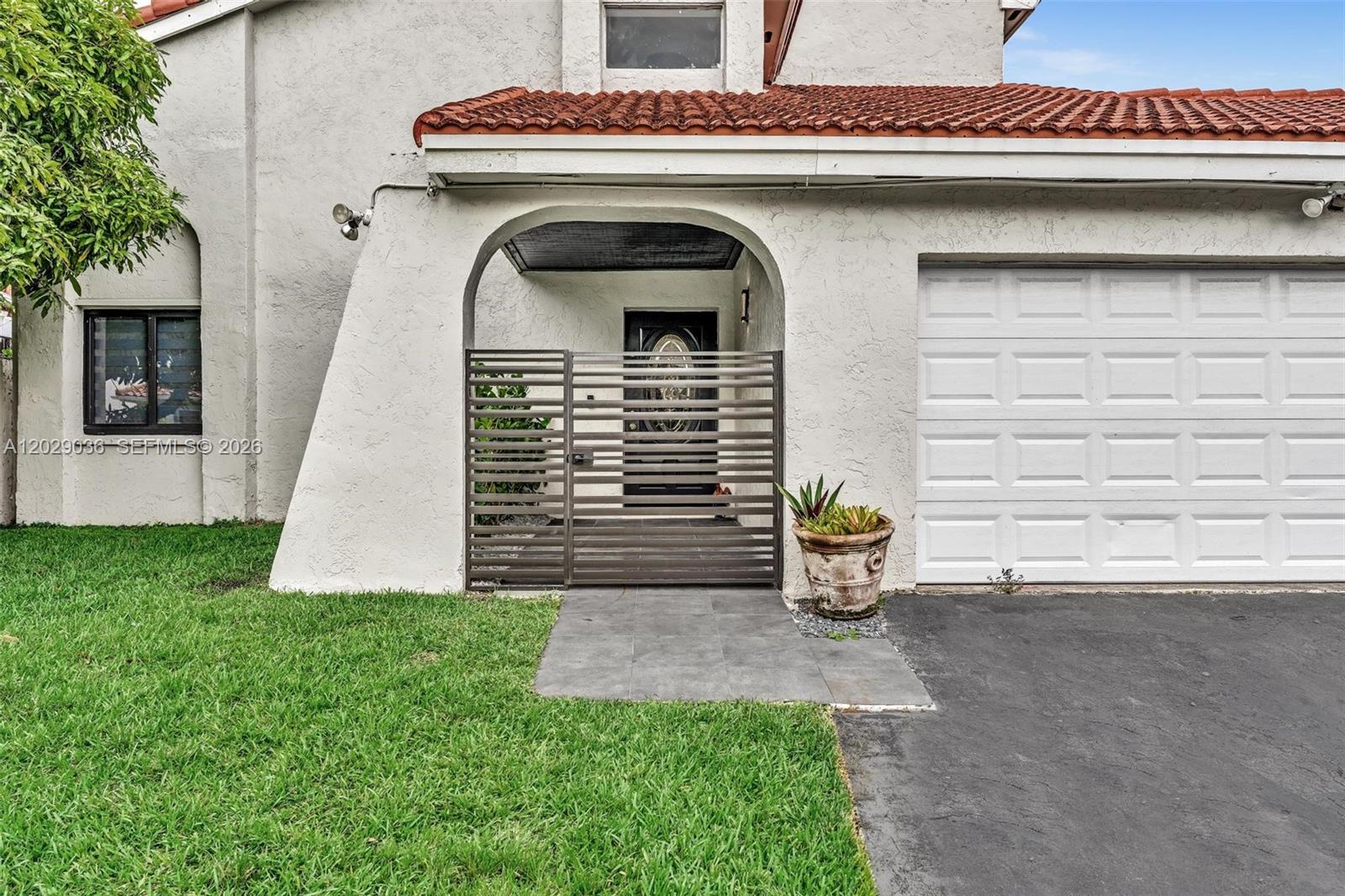 The exterior of a house features a gated entryway, a garage, and a tiled roof — 17532 NW 61st CT N, Hialeah FL 33015, HIALEAH, FL