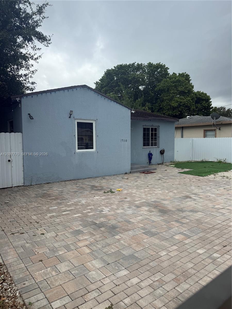 A light blue house with a paved driveway and a white fence — 1750 NW 55th Ter, Miami FL 33142, MIAMI, FL
