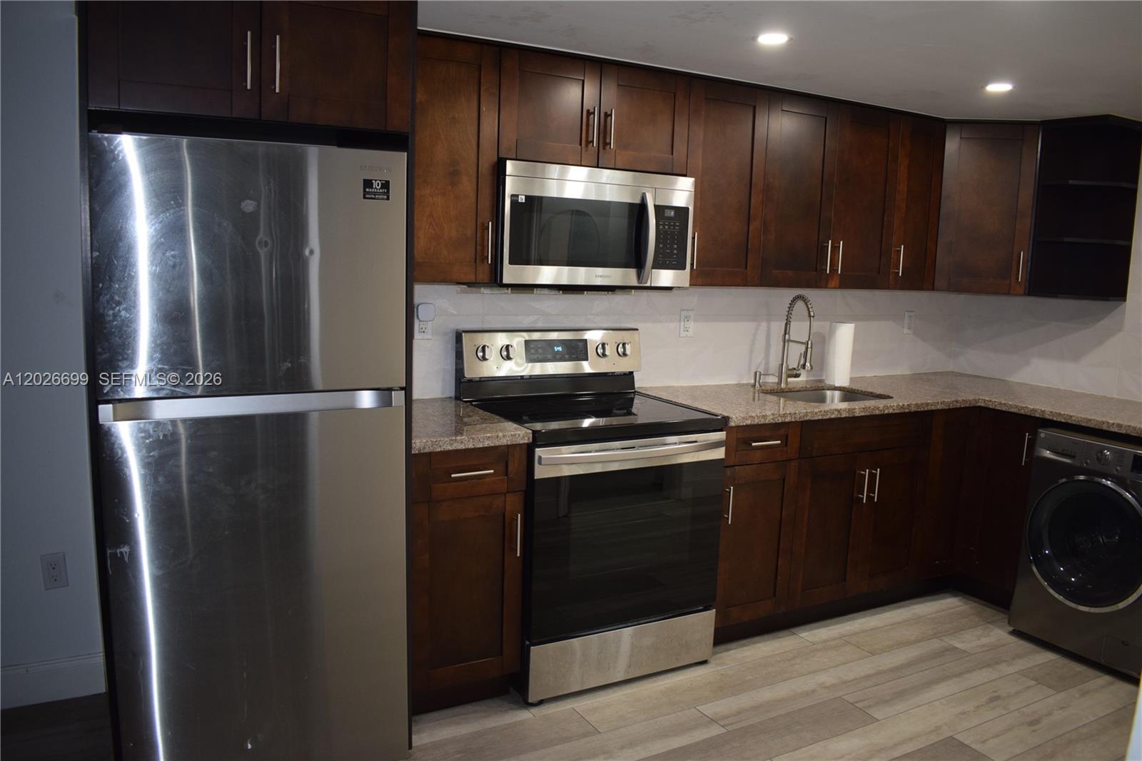 A kitchen features dark wood cabinets, stainless steel appliances, granite countertops, and a washing machine — 777 SW 9th Ave # 420, Miami FL 33130, MIAMI, FL