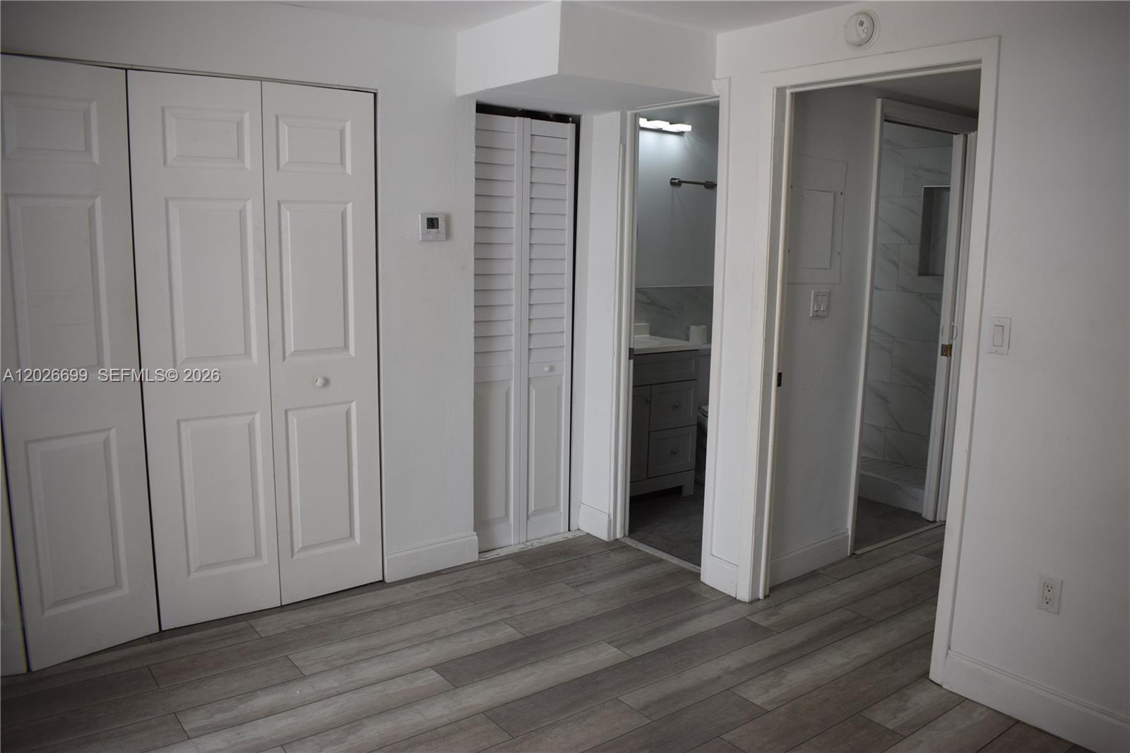 A room with wood-look flooring, white walls, closet doors, and an open bathroom doorway — 777 SW 9th Ave # 420, Miami FL 33130, MIAMI, FL