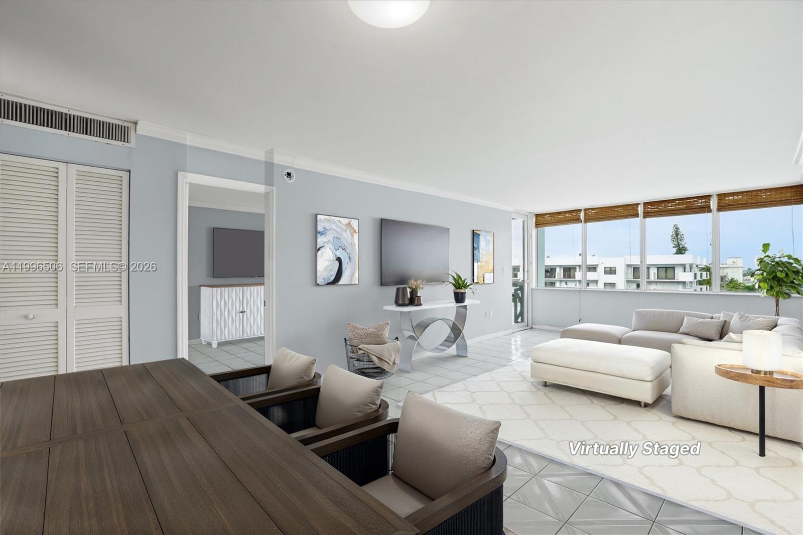 This living room features light blue walls, tile flooring, and large windows with exterior views — 8233 Harding Ave # 504, Miami Beach FL 33141, MIAMI BEACH, FL