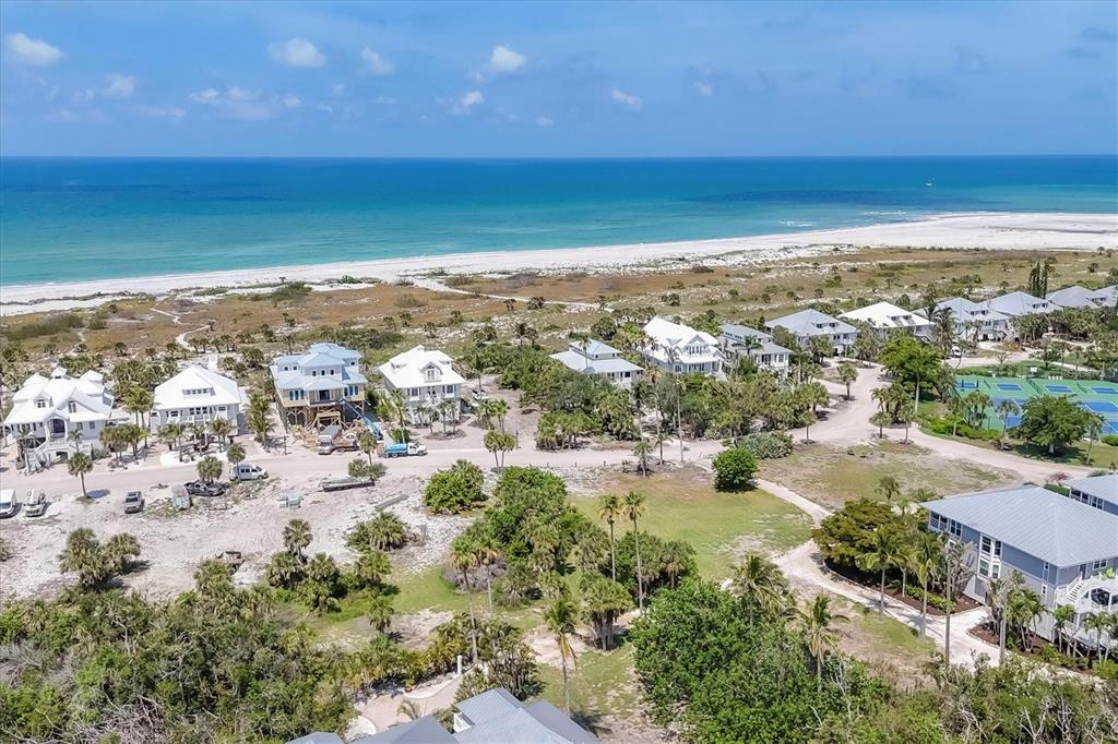 An aerial view shows several coastal houses near a sandy beach and the ocean — 7365 PALM ISLAND DRIVE, PLACIDA, FL