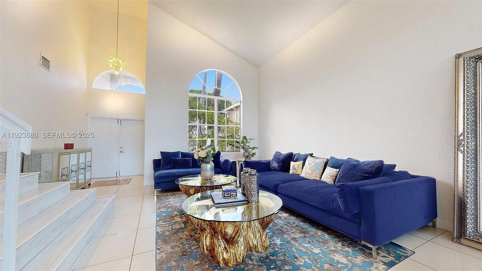 A living room features high ceilings, a large arched window, and blue velvet sofas — 14633 SW 132nd Ave, Miami FL 33186, MIAMI, FL