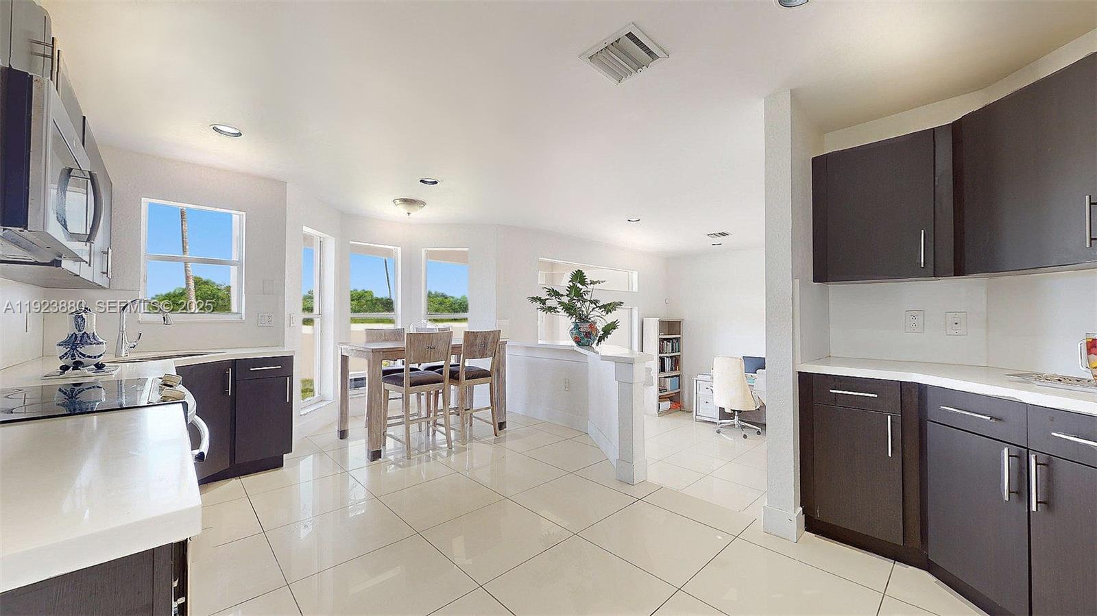 A kitchen with dark cabinets and white countertops opens into a dining and office area — 14633 SW 132nd Ave, Miami FL 33186, MIAMI, FL