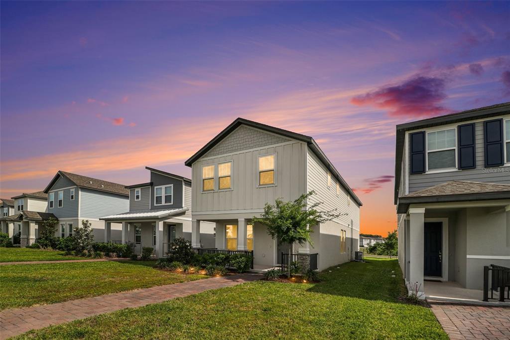 A row of modern suburban houses with paved walkways and green lawns at sunset — 14280 BRAEMAR STREET, WINTER GARDEN, FL