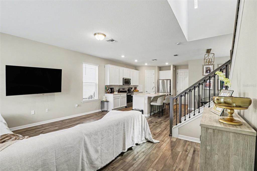 An open-concept living room and kitchen feature white cabinetry, stainless appliances, and wood-look flooring — 14280 BRAEMAR STREET, WINTER GARDEN, FL