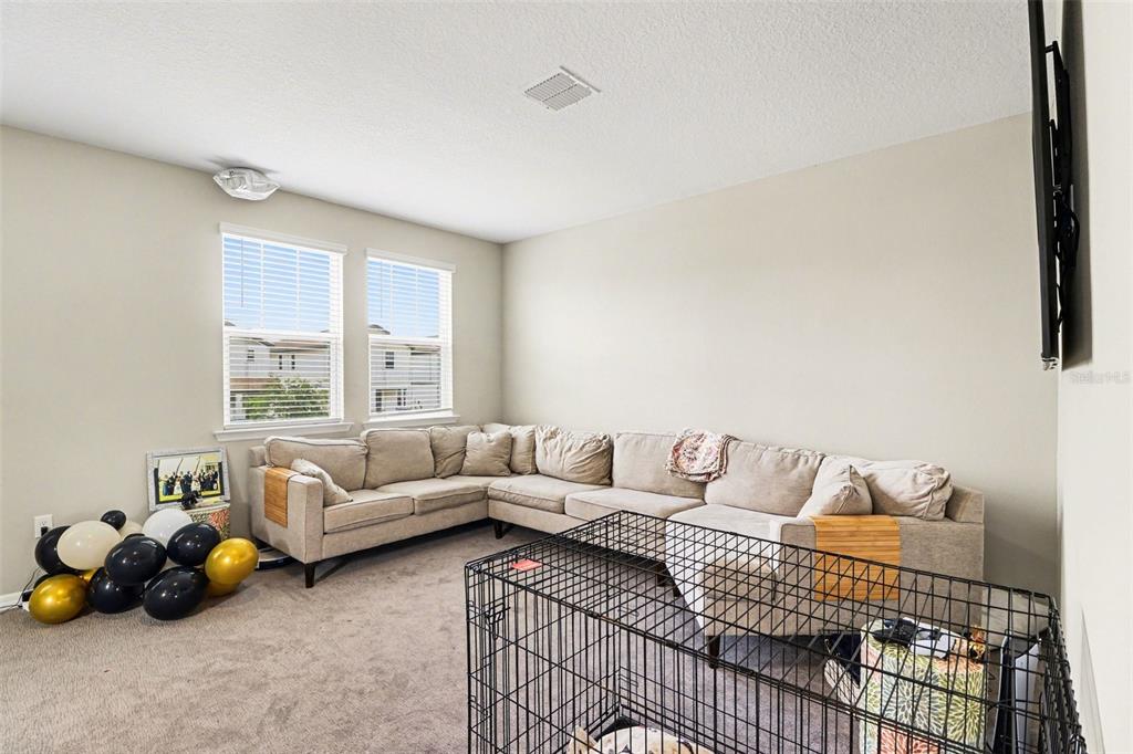 A living room features a large beige sectional sofa, carpeted floors, and a dog crate — 14280 BRAEMAR STREET, WINTER GARDEN, FL