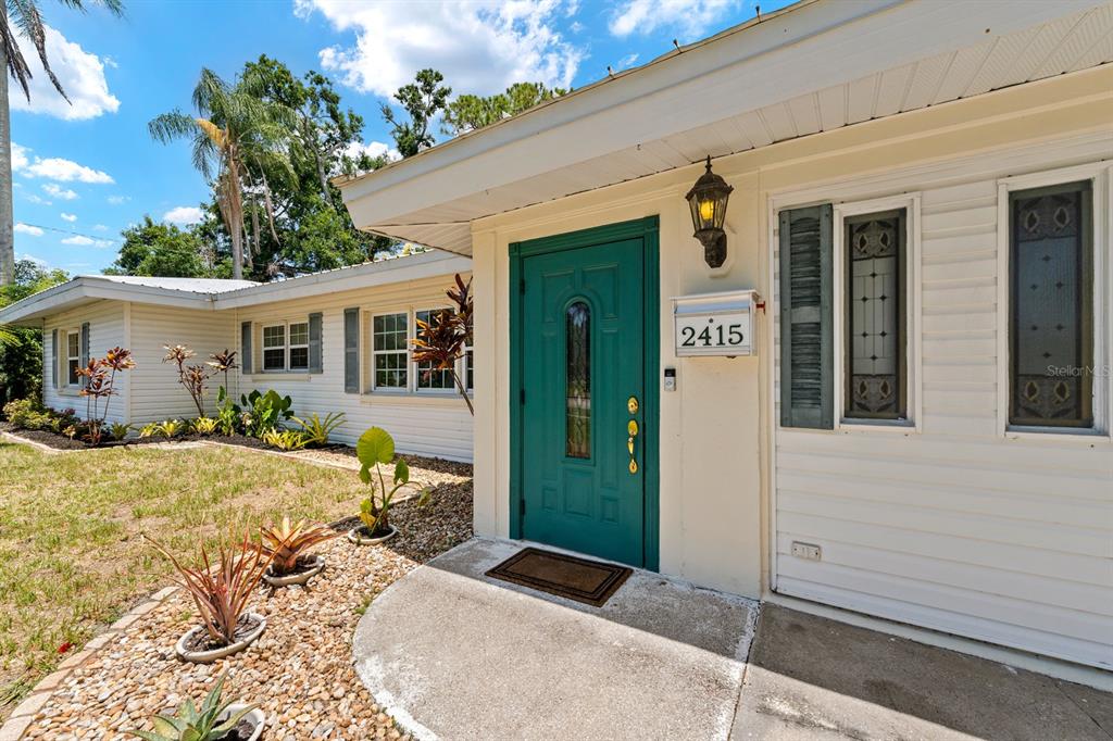 A teal front door with a house number sits on the exterior of a house — 2415 2ND AVENUE E, BRADENTON, FL