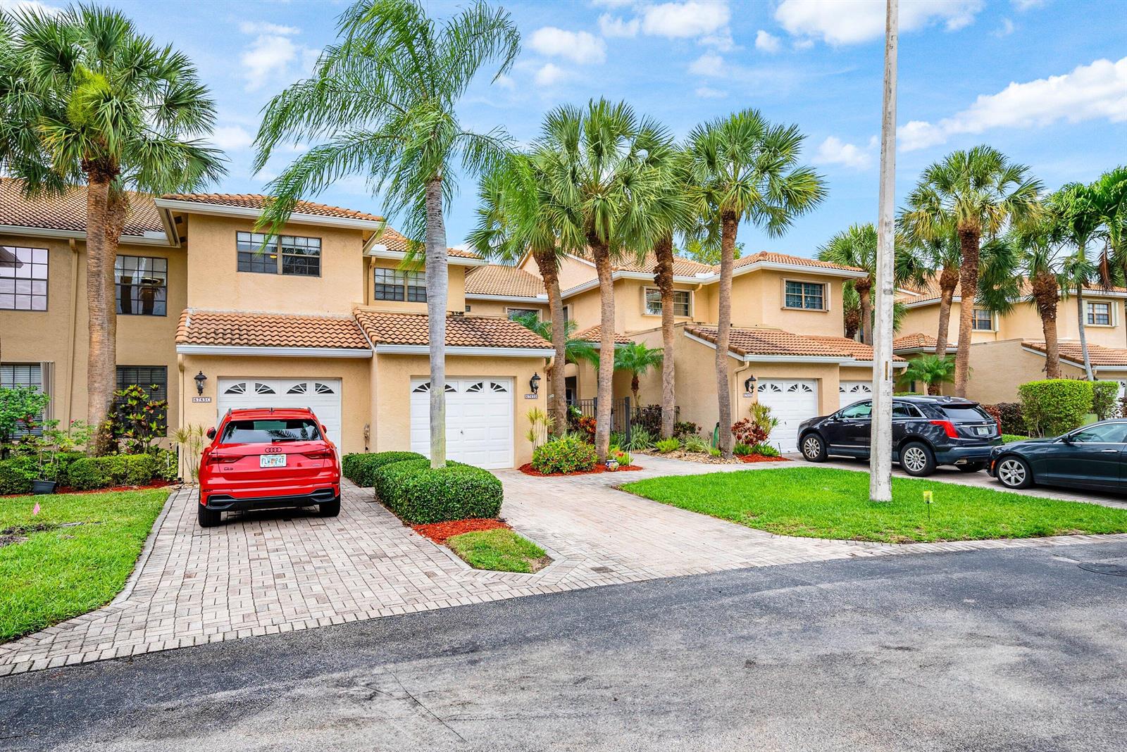 A row of tan townhouses with tile roofs, palm trees, and cars parked in the driveways — 6765 Montego Bay Boulevard # D, Boca Raton FL 33433, BOCA RATON, FL