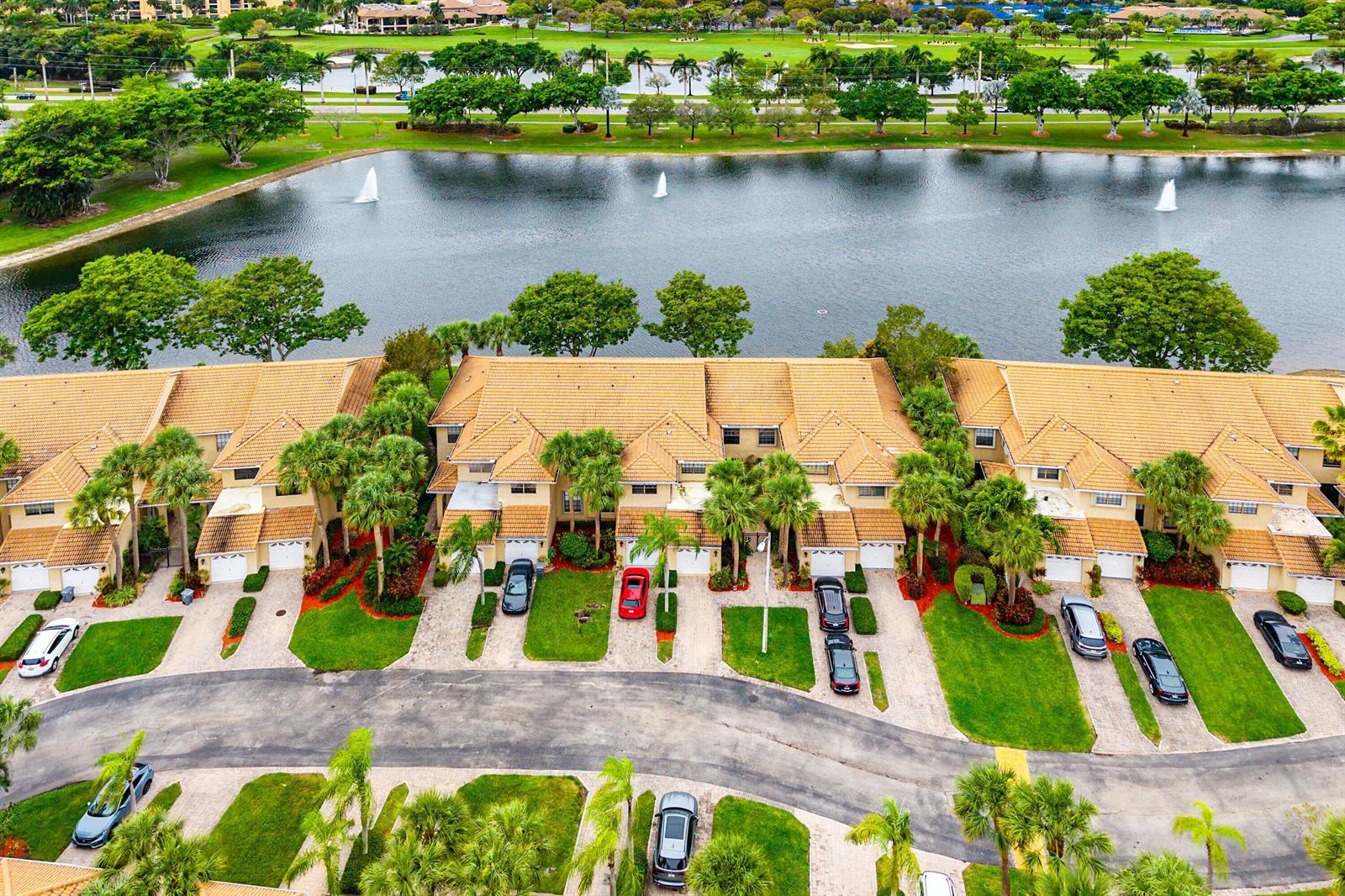 An aerial view shows a row of townhouses with tiled roofs overlooking a large lake — 6765 Montego Bay Boulevard # D, Boca Raton FL 33433, BOCA RATON, FL