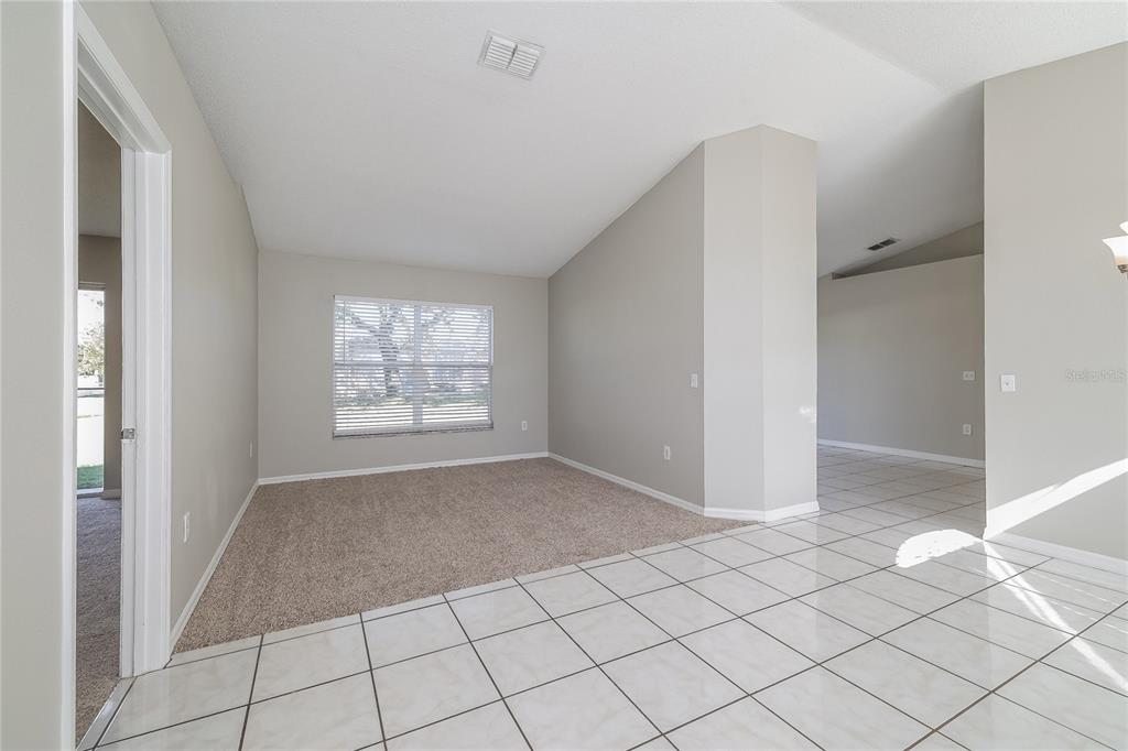 A room with beige carpet and a tiled entryway features a window with blinds — 188 ANZIO DRIVE, KISSIMMEE, FL