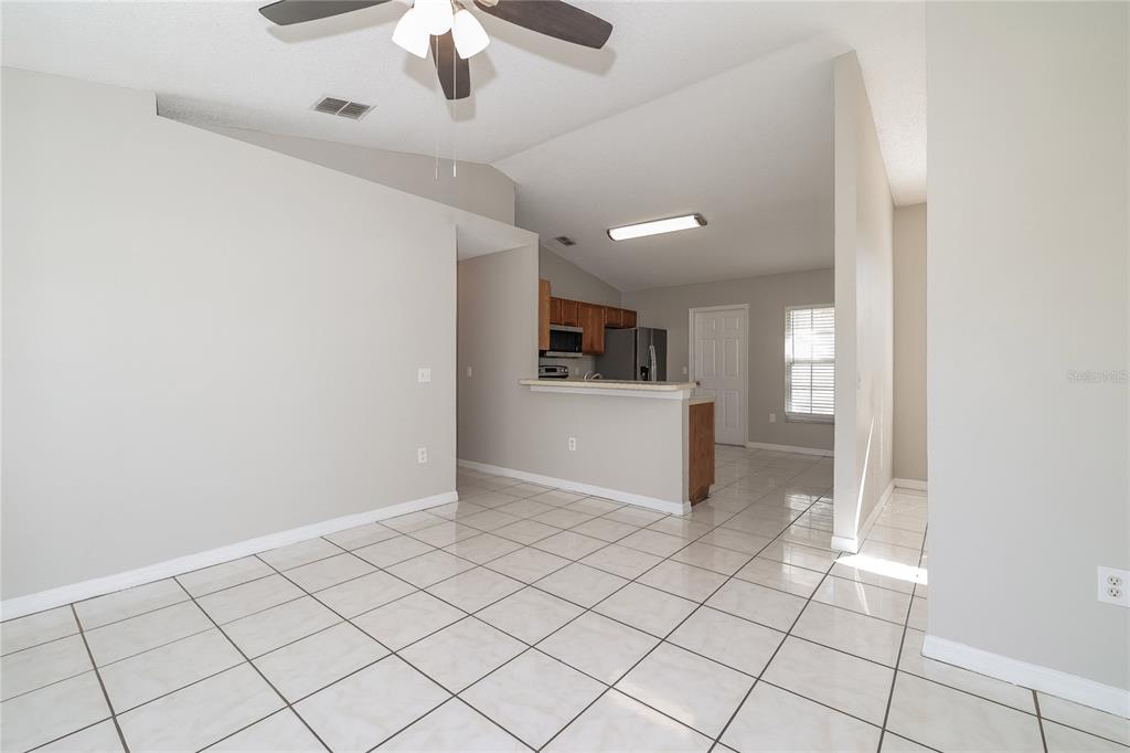 A tiled dining area opens to a kitchen with wooden cabinets and a breakfast bar — 188 ANZIO DRIVE, KISSIMMEE, FL