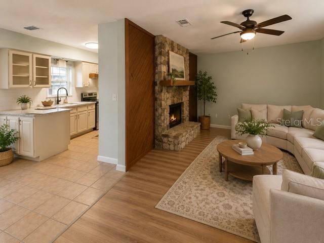 An open-concept kitchen and living room featuring a stone fireplace and light wood flooring — 2161 NE 38 STREET, OCALA, FL