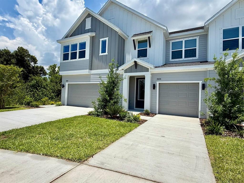 A two-story duplex with gray and white siding, two garage doors, and concrete driveways — 6404 JENSEN VIEW AVENUE, APOLLO BEACH, FL