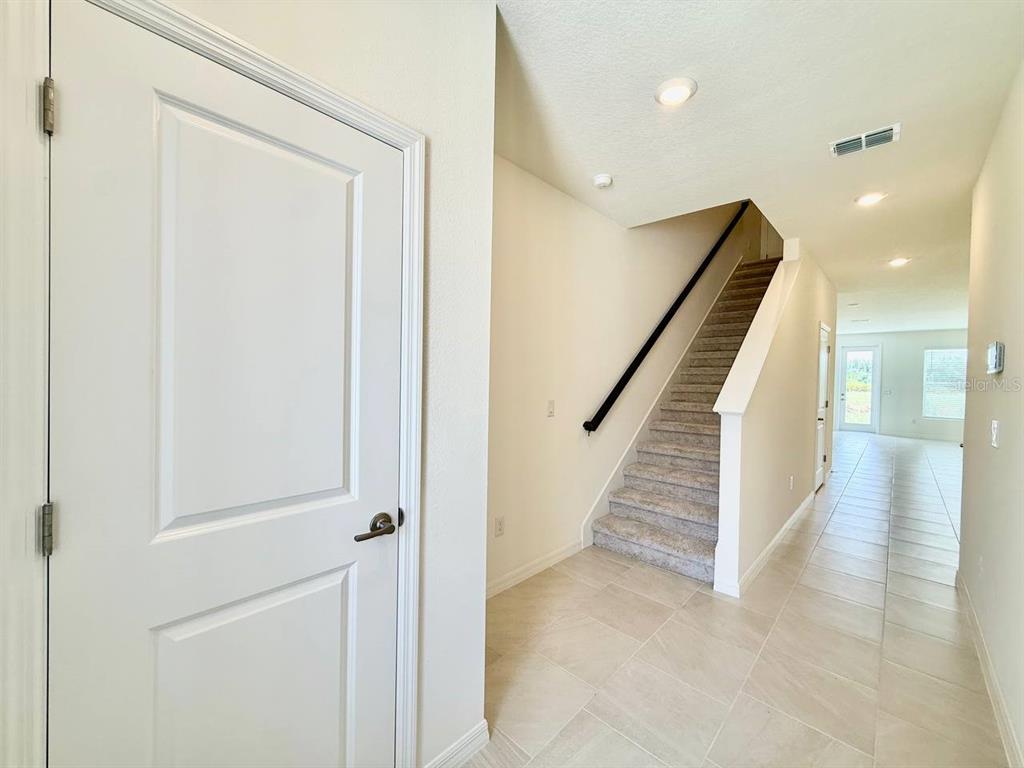 An entryway features a white door, a carpeted staircase, and light-colored tile flooring — 6404 JENSEN VIEW AVENUE, APOLLO BEACH, FL