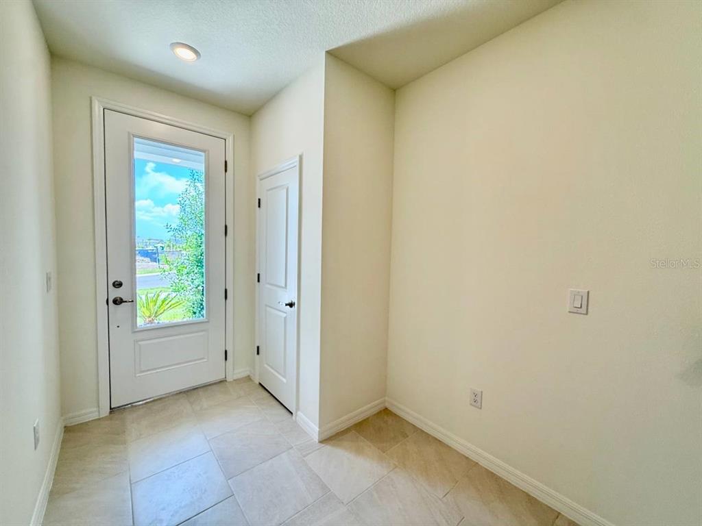 An entryway with tile flooring, a white front door with a glass panel, and a closet — 6404 JENSEN VIEW AVENUE, APOLLO BEACH, FL