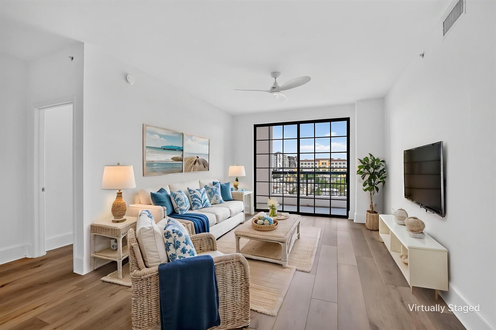 A living room features a white sofa, wicker furniture, a television, and large black-framed balcony doors — 233 S Federal Highway # 623, Boca Raton FL 33432, BOCA RATON, FL