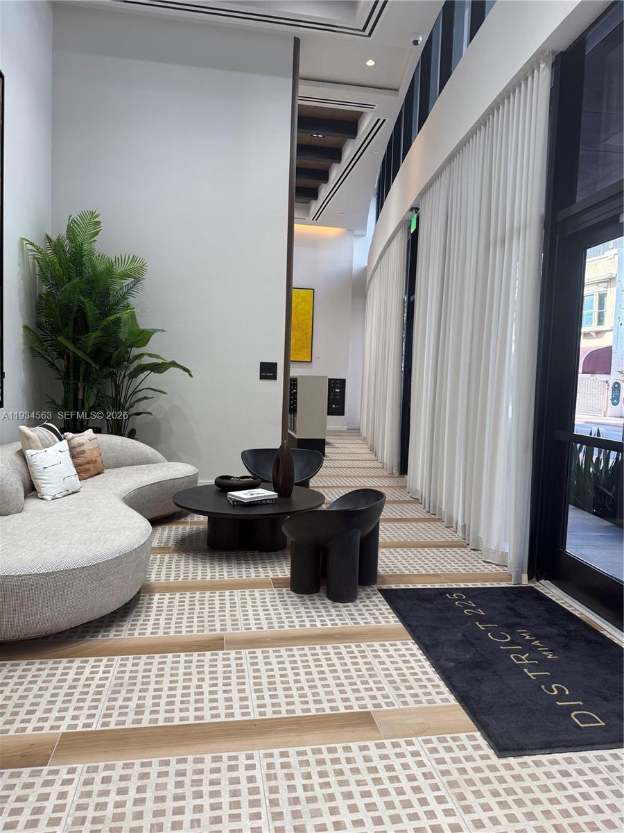 A modern lobby features a curved sofa, dark sculptural chairs, and patterned tile flooring — 225 N Miami ave # 501, Miami FL 33128, MIAMI, FL