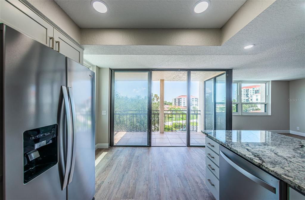 A kitchen with stainless steel appliances and granite countertops opens to a balcony with views — 6177 SUN BOULEVARD UNIT 404, ST PETERSBURG, FL