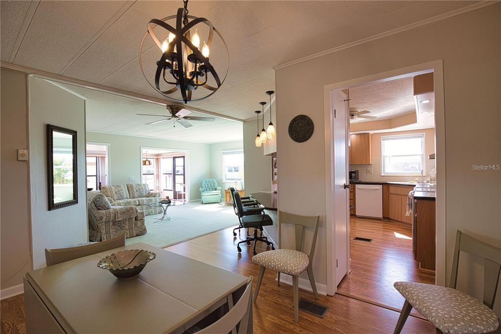 A dining area with a chandelier overlooks a living room and a kitchen beyond — 402 CHIQUITA, NORTH PORT, FL