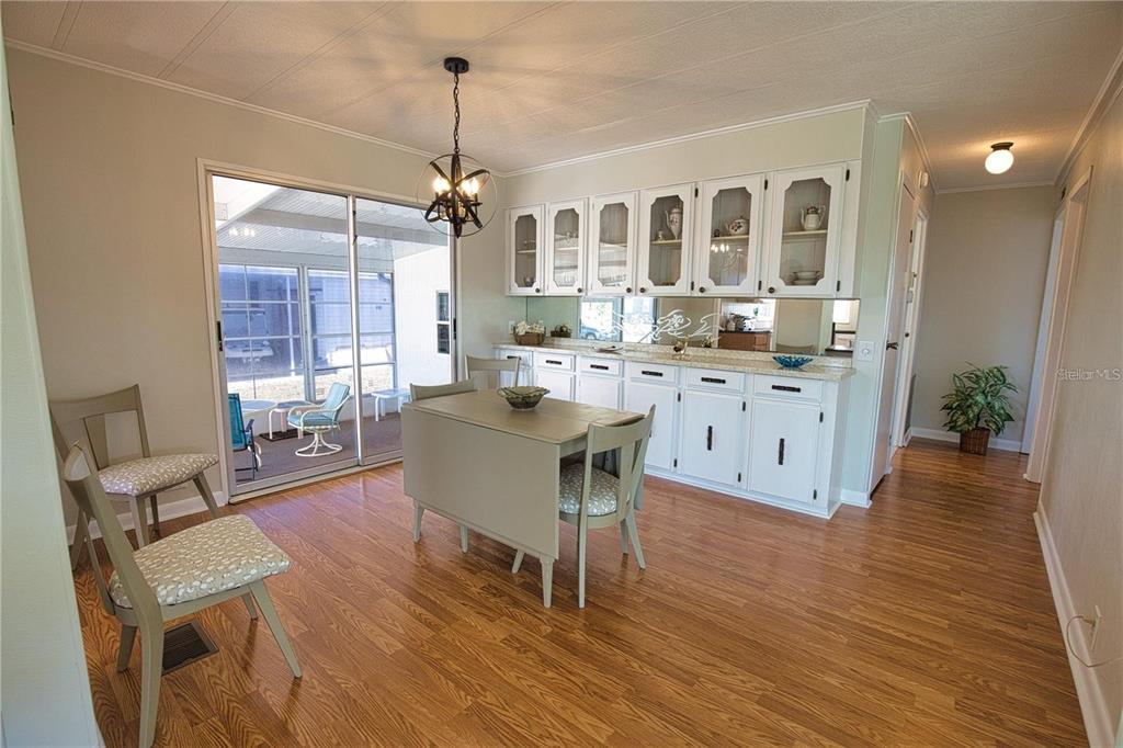 A dining area with wood flooring, a white hutch, and a sliding glass door — 402 CHIQUITA, NORTH PORT, FL