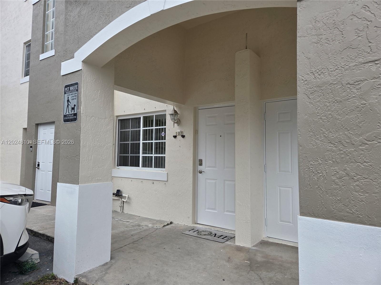 The exterior of a residential building features a covered entryway with two white doors — MIAMI, FL
