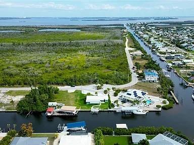 An aerial view shows waterfront homes along a canal adjacent to a large grassy field — 2891 CUSSELL DRIVE, ST JAMES CITY, FL