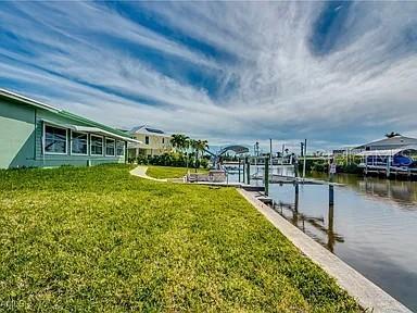 A waterfront house with a green exterior sits beside a canal with a boat dock — 2891 CUSSELL DRIVE, ST JAMES CITY, FL