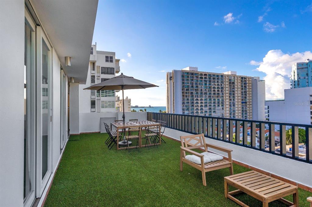A balcony with artificial turf, outdoor dining furniture, and a view of the ocean — 7 CALLE ROSA UNIT PH, CAROLINA, PR