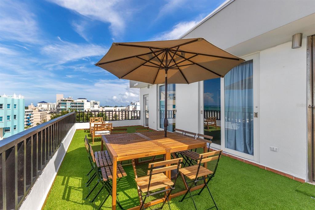 A rooftop terrace features artificial turf, a wooden dining set with an umbrella, and railings — 7 CALLE ROSA UNIT PH, CAROLINA, PR