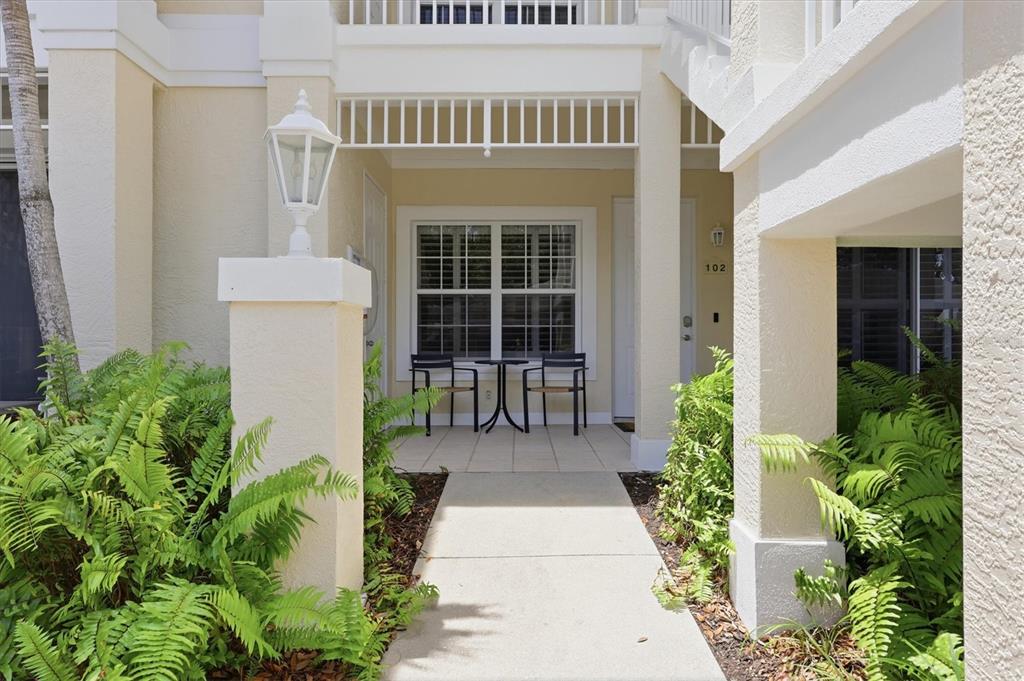 A concrete walkway leads to the covered patio entrance of a ground-floor unit — 3510 54TH DRIVE W UNIT 102, BRADENTON, FL