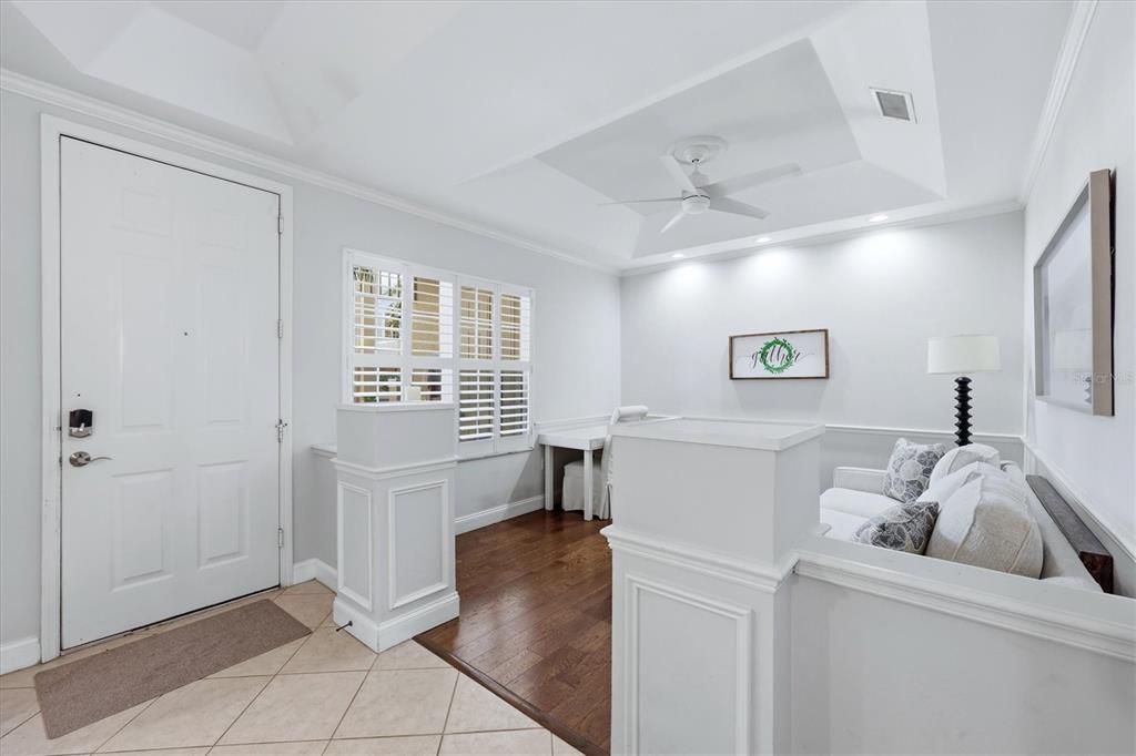 An entryway with tile flooring leads to a sunken living area with hardwood floors — 3510 54TH DRIVE W UNIT 102, BRADENTON, FL