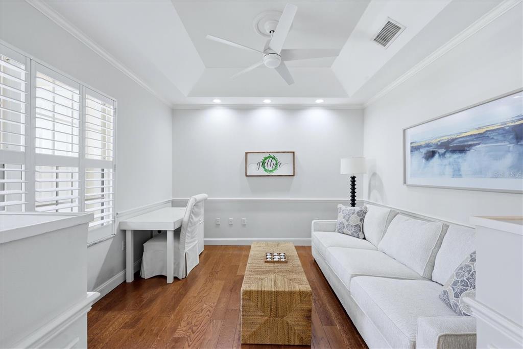 A bright living room features a white sofa, a woven coffee table, and a desk — 3510 54TH DRIVE W UNIT 102, BRADENTON, FL