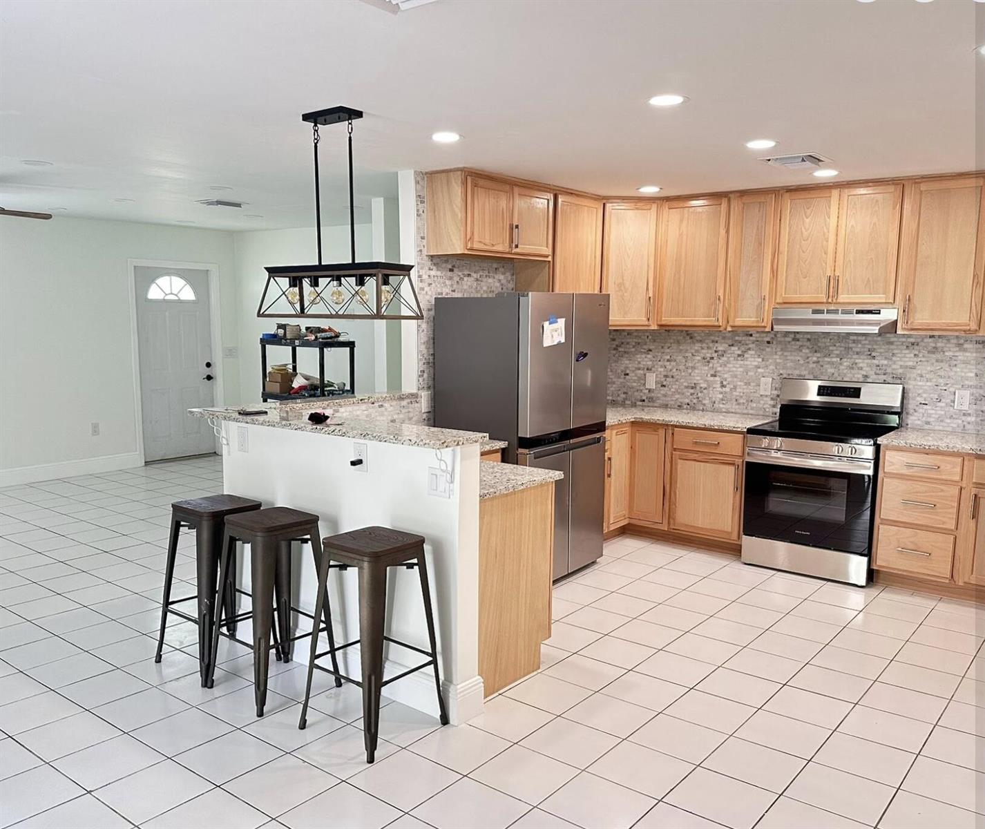 A kitchen with light wood cabinets, granite countertops, stainless steel appliances, and a breakfast bar — 117 Yacht View Lane, FL 34946, FL