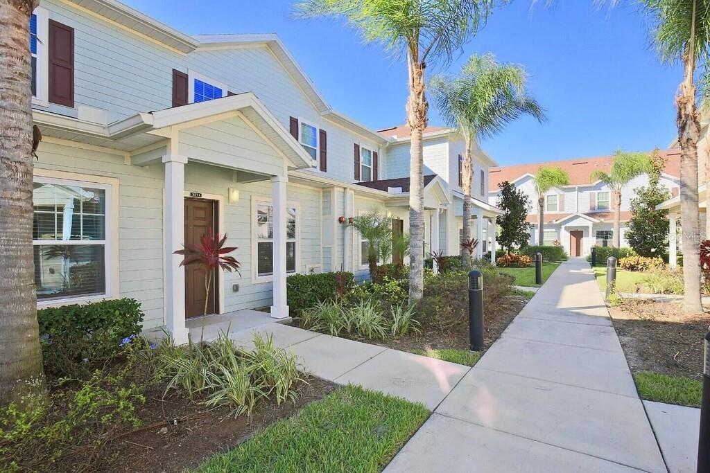 A light blue two-story townhouse exterior with a front walkway and palm trees — 3211 WISH AVENUE, KISSIMMEE, FL