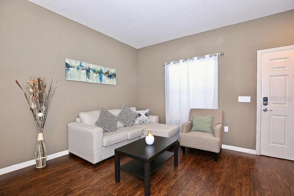 A living room features a light gray sectional sofa, an armchair, and a dark coffee table — 3211 WISH AVENUE, KISSIMMEE, FL