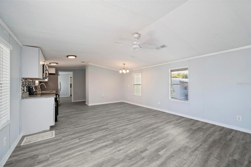 An open-concept living area features light gray walls, wood-look flooring, and an adjacent kitchen — 1000 KINGS HIGHWAY UNIT 101, PORT CHARLOTTE, FL